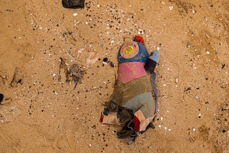 Primer plano de un muñeco de trapo tirado en la arena de la playa como residuo o basura. Phu Quoc