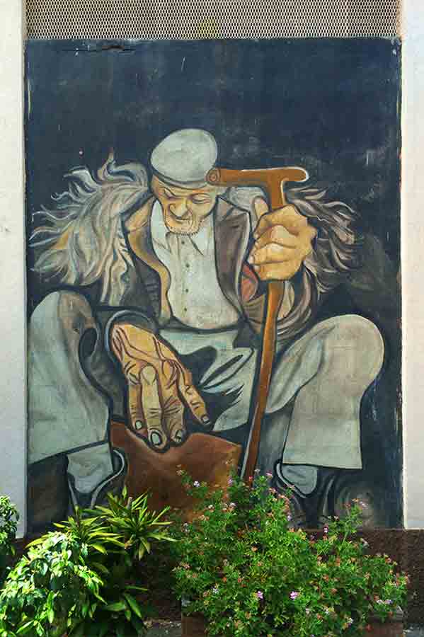 Pintura mural donde vemos un señor mayor con un bastón. Orgosolo. Cerdeña.