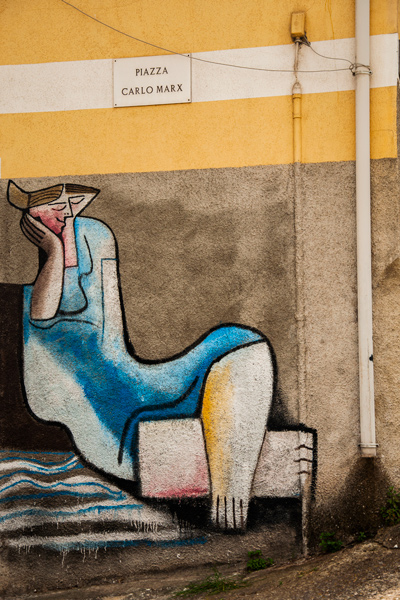 Pintura mural en la Plaza de Carlo Marx donde vemos a una mujer descansando sobre su brazo derecho. Orgosolo. Cerdeña.