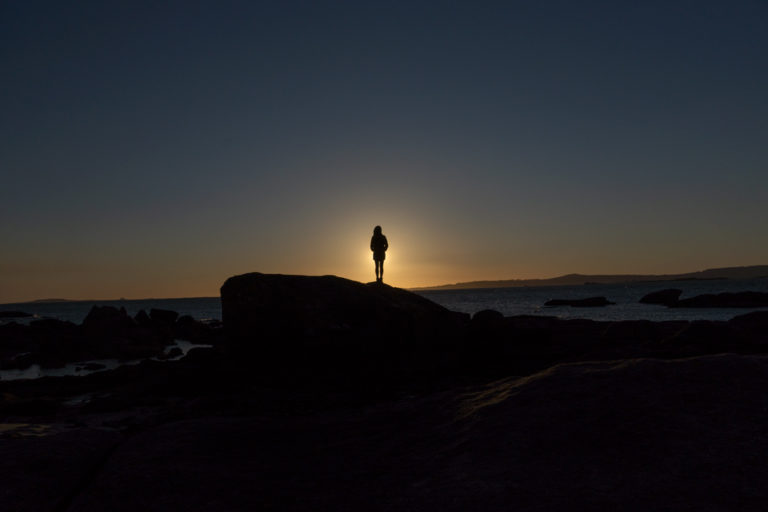 Puesta de sol donde una chica mira misteriosa al horizonte. 20 sorprendentes curiosidades de Galicia. Perder el Rumbo