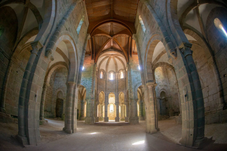 Hermosos interior de un monasterio de piedra con bellos capiteles y columnas y una hermosa luz que ilumina el lugar entrando por las pequeñas ventanas. Monasterio de Carboeiro. Visita, ruta y leyenda en Silleda