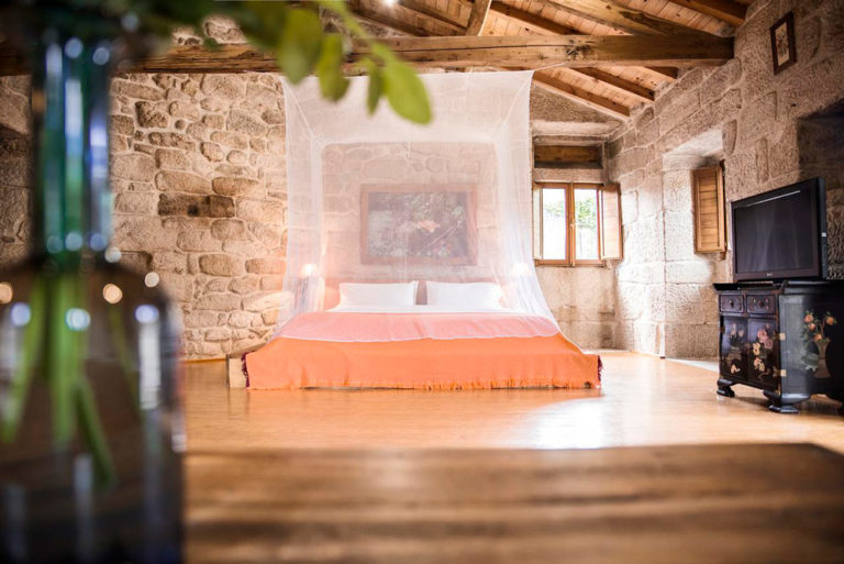 Preciosa habitación con una enorme cama con mosquitera. Paredes de piedra y techos de madera. 10 casas rurales en Ourense con mucho encanto. Perder el RumboCasas rurales en Ourense con encanto. Perder el Rumbo