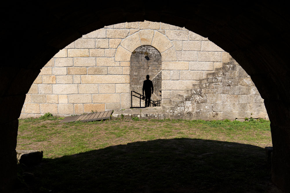 Una silueta se dibuja en la puerta de un castillo medieval de piedra. 10 lugares imprescindibles qué ver en Castro Caldelas y alrededores. Perder el Rumbo