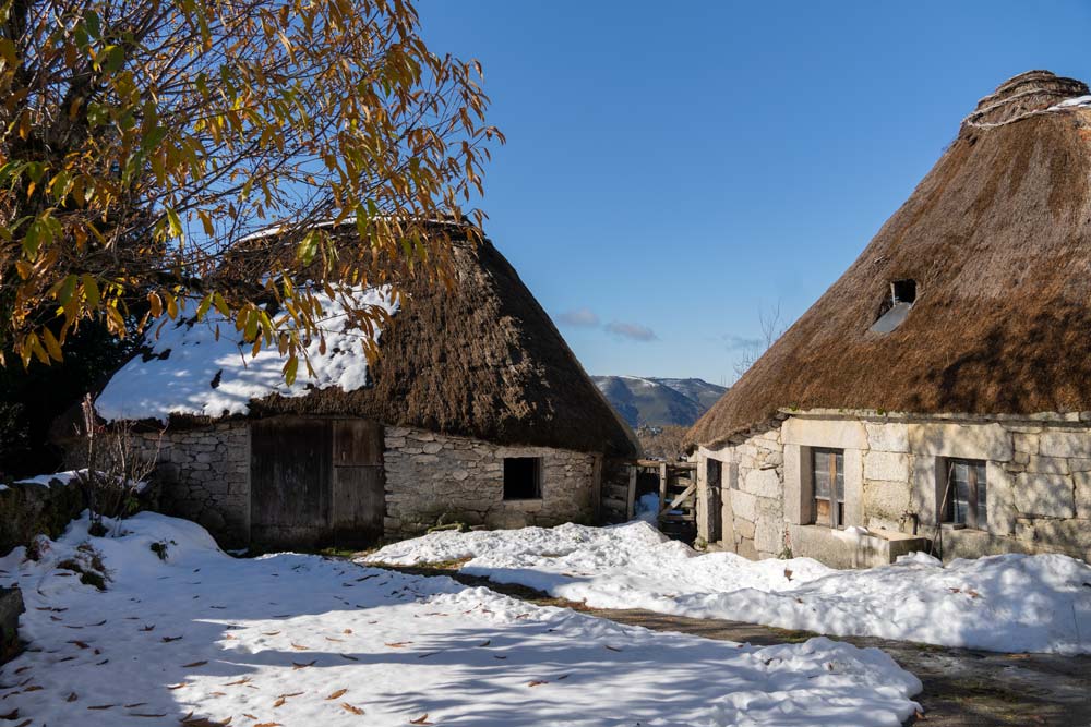Dos Pallozas tradicionales, casas de planta redonda con muros de piedra y tejados de paja rodeados de nieve. ¿Qué ver en Galicia en invierno? 10 escapadas invernales. Qué ver en Galicia en invierno. Perder el Rumbo.