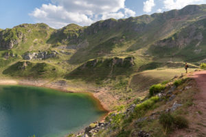 Chico que camino por una ruta al borde de un lago. Rutas en Asturias. Perder el Rumbo