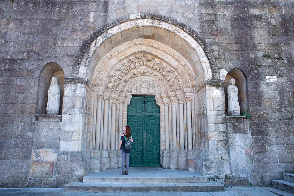 Chica que contempla la puerta y las esculturas de la iglesia de Santa María de Azogue. 