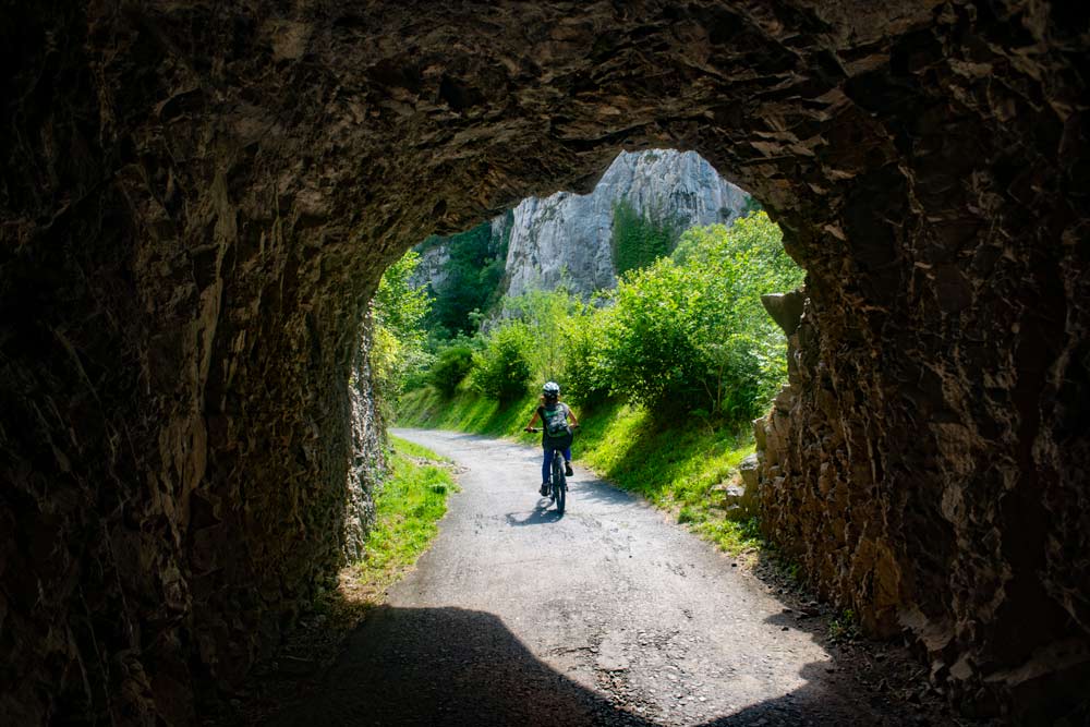 Una ciclista sale de un túnel del desfiladero de Valdecerezales en la Senda del Oso.