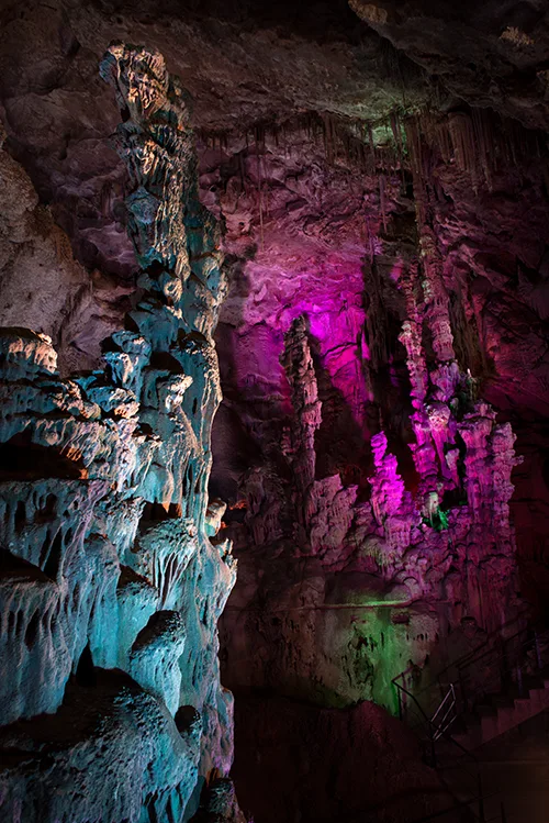 Estalactitas y estalacmtita tintadas con luz de colores en el interior de una cueva.s 