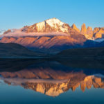 El macizo del Paine con sus torres se refleja en un lago a modo de espejo. La luz de la mañana está iluminando las partes altas de las torres. parque nacional Torres del Paine.