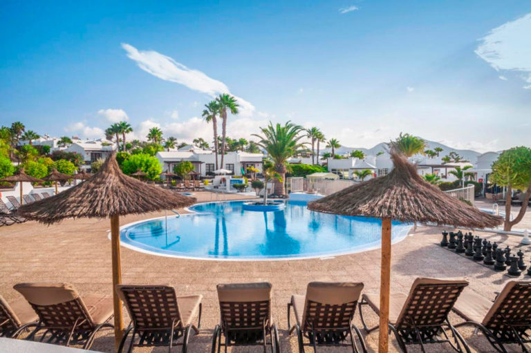 Hotel con casitas blancas rodeado de plameras y con una gran piscina.Hoteles en Lanzarote. Perder el Rumbo