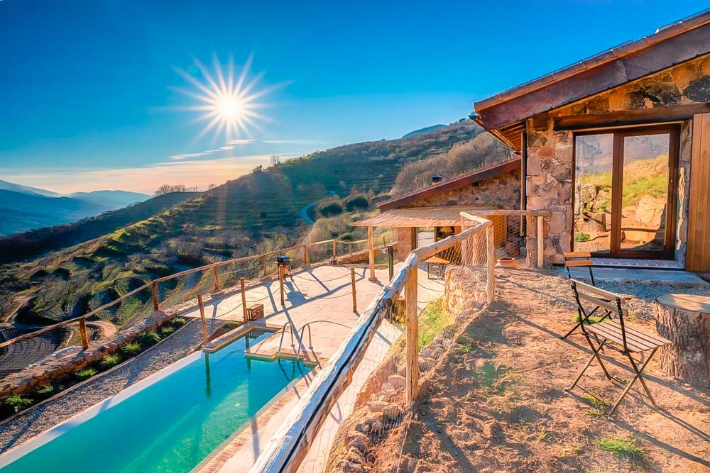 Una casa rural con una piscina e un día soleado con vistas a la montaña. Una Escapadas Rurales en España de lujo.