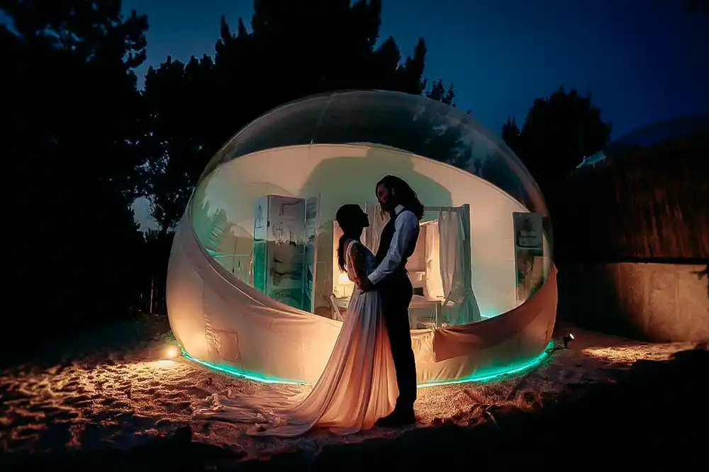 Dos personas se abrazan de noche delante de uno de los hoteles burbuja en Galicia