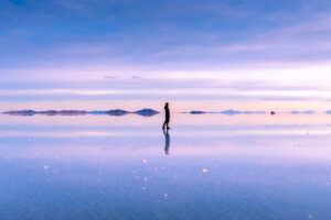 Lucias mira hacia el horizonte en un gran espejo natural de agua en el salar de Uyuni.