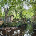 Paisaje verde con un molino de agua restaurado y un puente de madera en el Refuxio de Verdes en Coristanco, A Coruña.