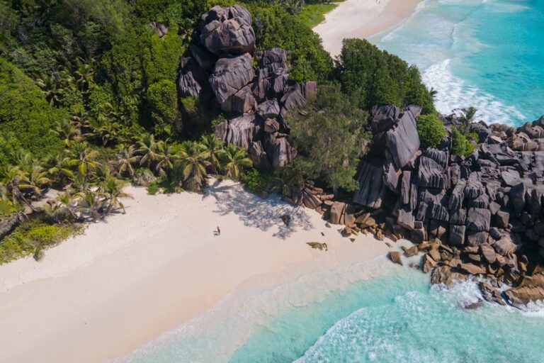 Plano aéreo de una playa de La Digue con arena blanca, aguas turquesas y rocas graníticas de formas impresionantes. Es una auténtica belleza, un paraíso. Esta foto es la portada del artículo Qué ver y qué hacer en La Digue, de Perder el Rumbo.
