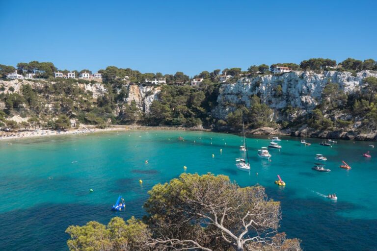 Vista de Cala Galdana con su preciosa playa de aguas turquesas y sus acantilados con casitas en la cima. Sin duda, una de las mejores zonas donde alojarse en Menorca