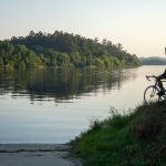 Vistas del rio desde la Ecopista del Miño al amanecer, con bicicleta de carretera apoyada junto a la orilla.