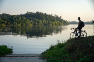 Vistas del rio desde la Ecopista del Miño al amanecer, con bicicleta de carretera apoyada junto a la orilla.