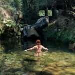 Lucía bañándose en las aguas cristalinas de las Lagoas de Travanca, rodeada de rocas cubiertas de musgo.